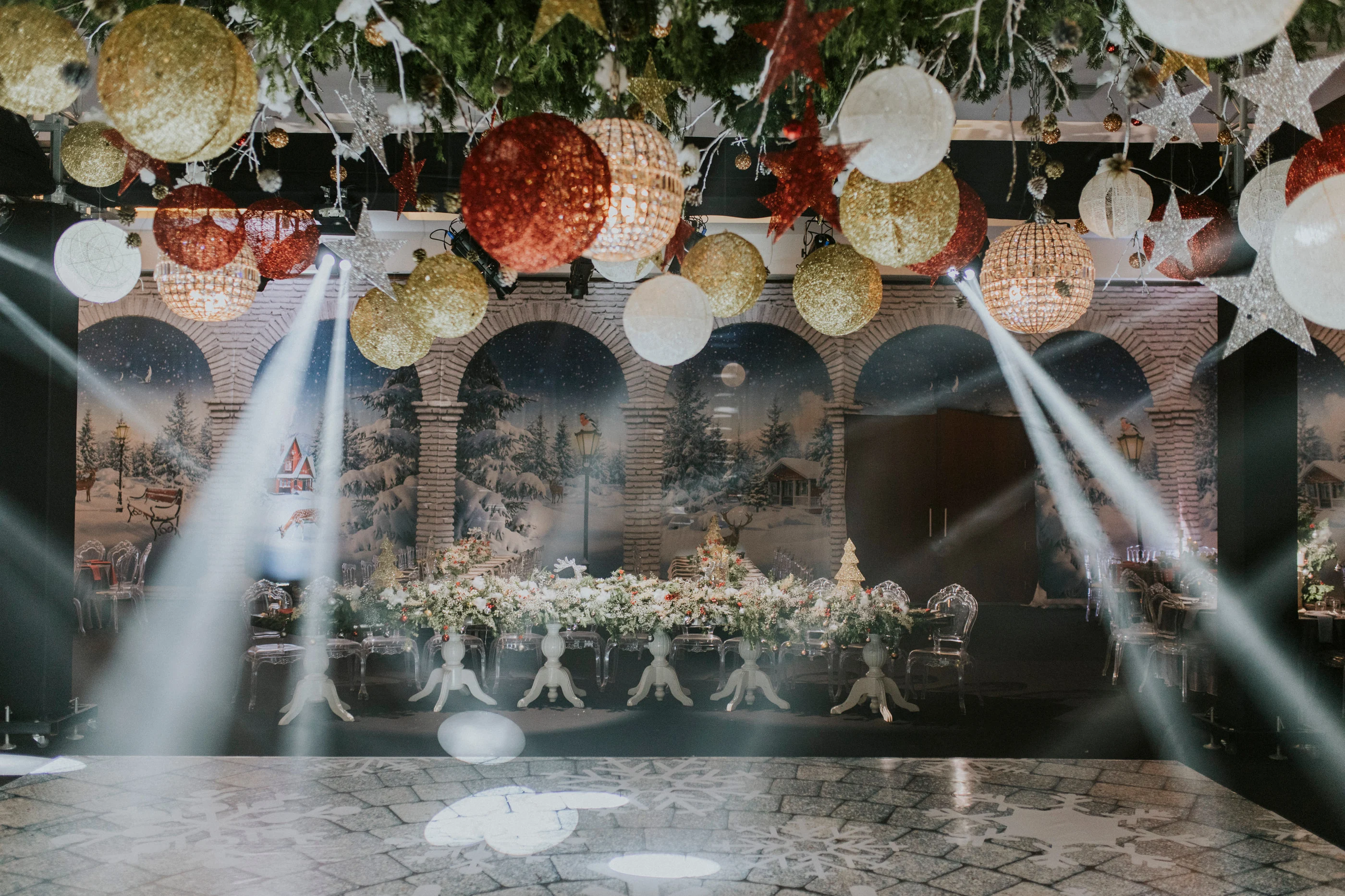Empty dance floor lit by light beams beneath large glittering hanging baubles