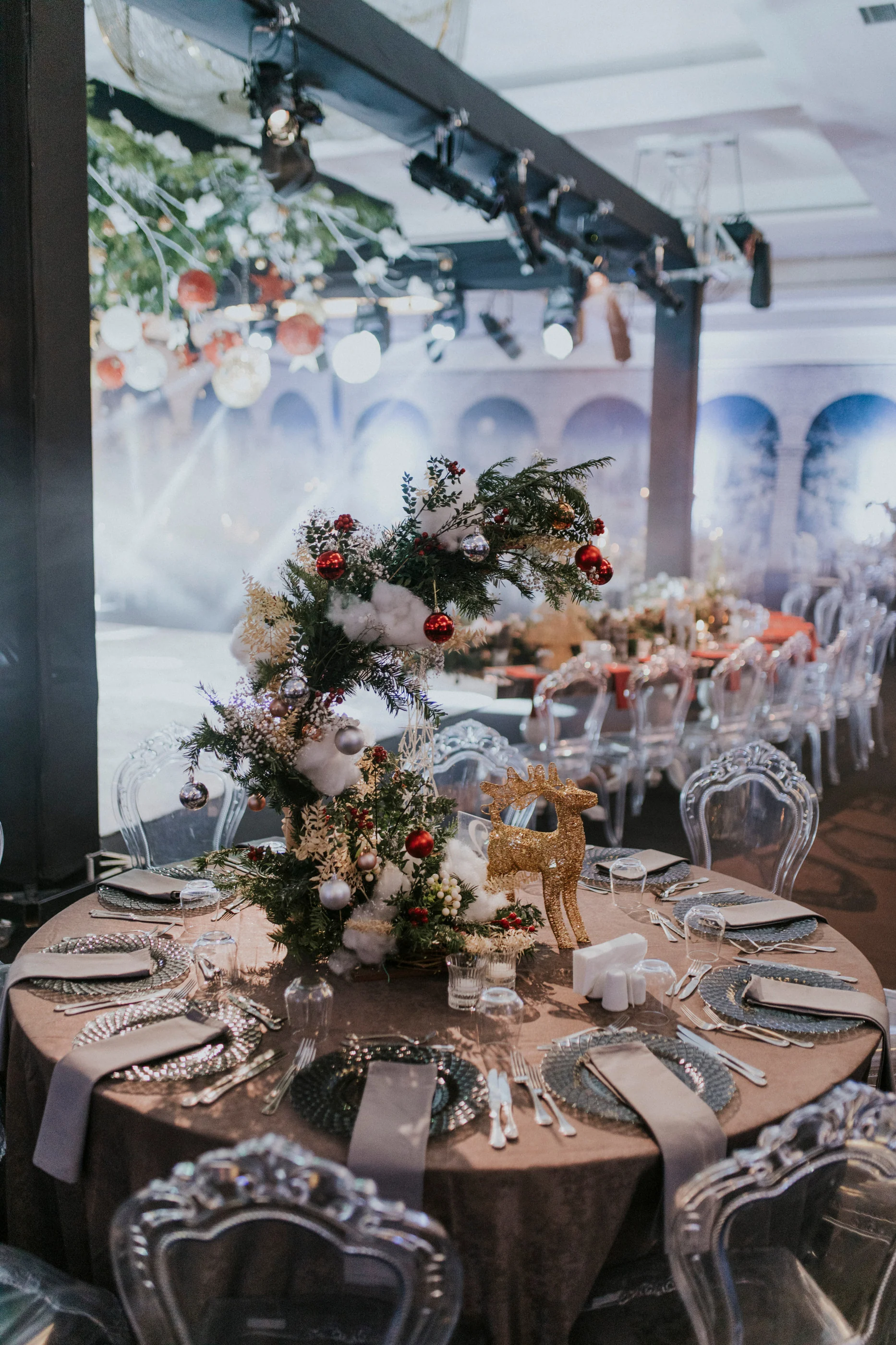 Raised pine and red ornament arrangement on a round table with a brown cloth