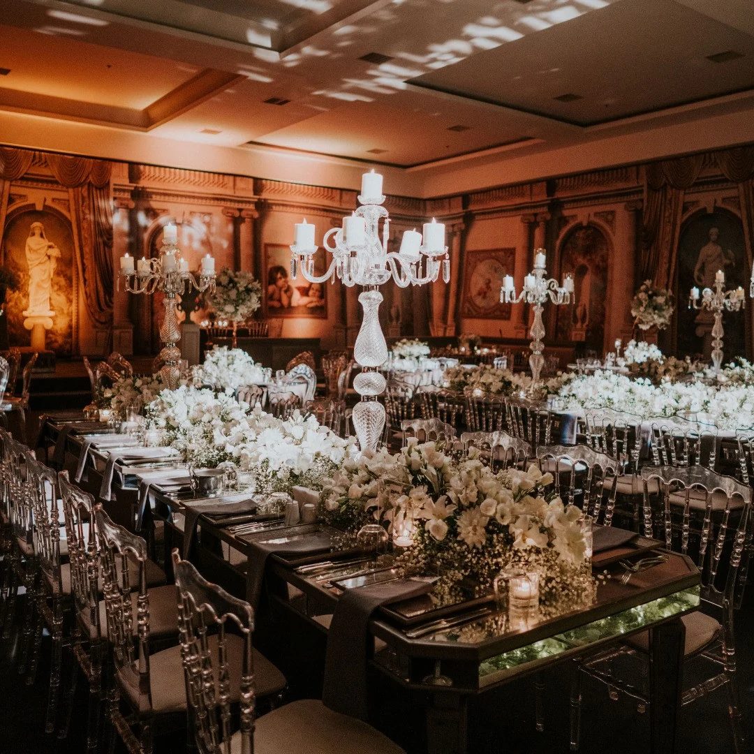 Long tables with crystal candelabras and white flowers in a warmly lit fresco hall