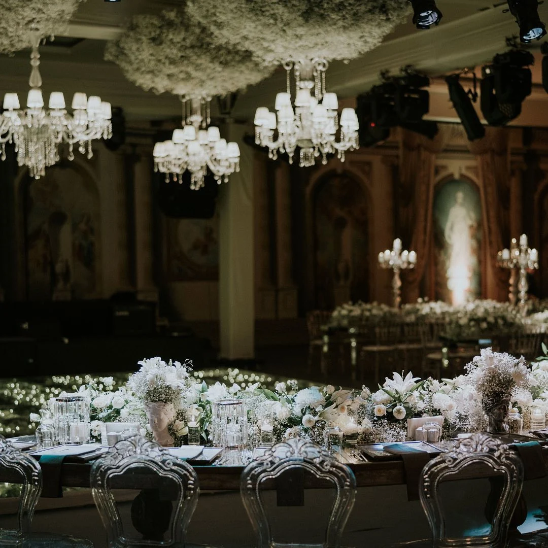 Crystal chandeliers hanging from a white floral cloud ceiling over a dim dance area