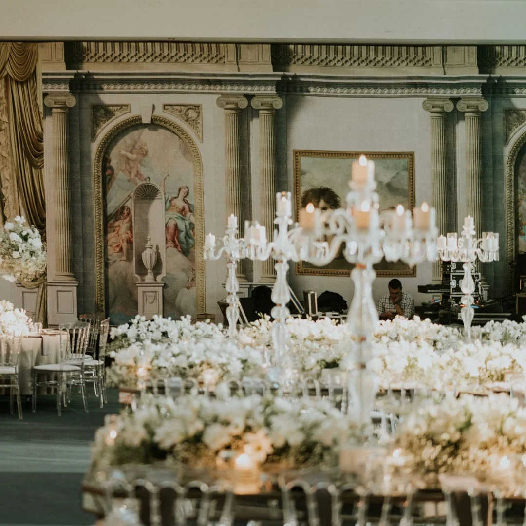Crystal candelabra with candles and white floral arrangements before a fresco wall