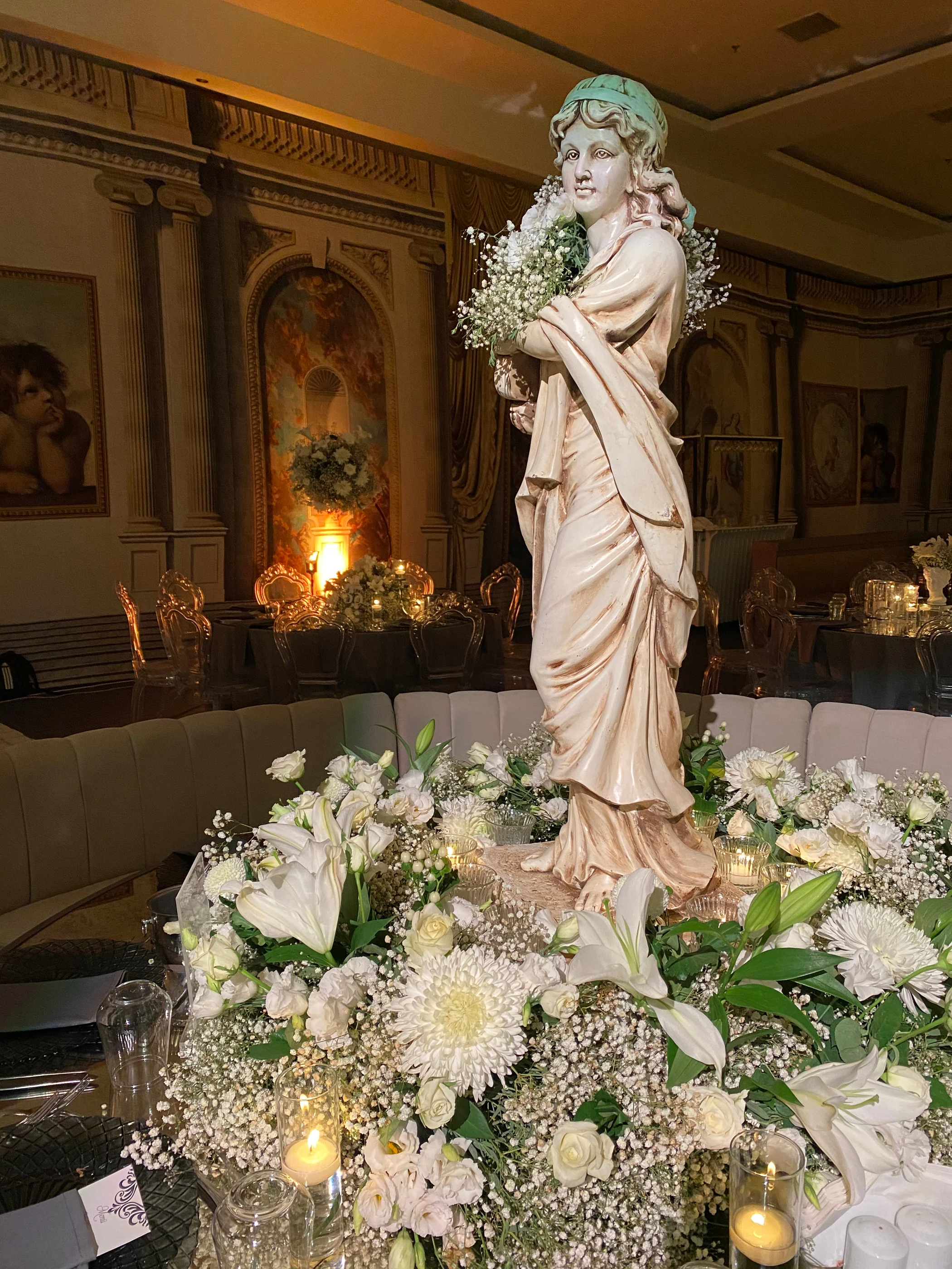 Close-up of a statue holding flowers amid white lilies and baby's breath