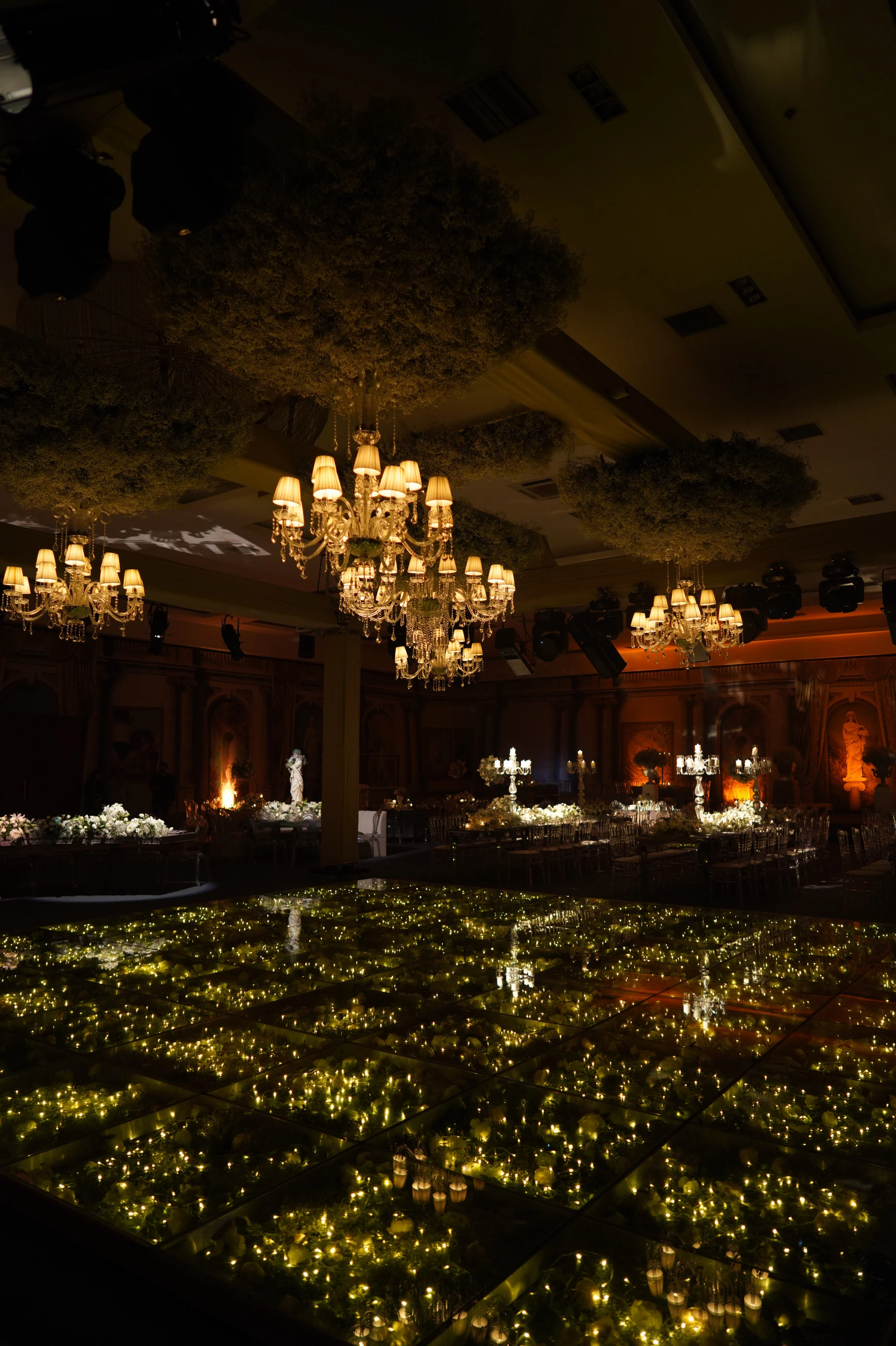 Dark dance floor sparkling with tiny lights beneath crystal chandeliers