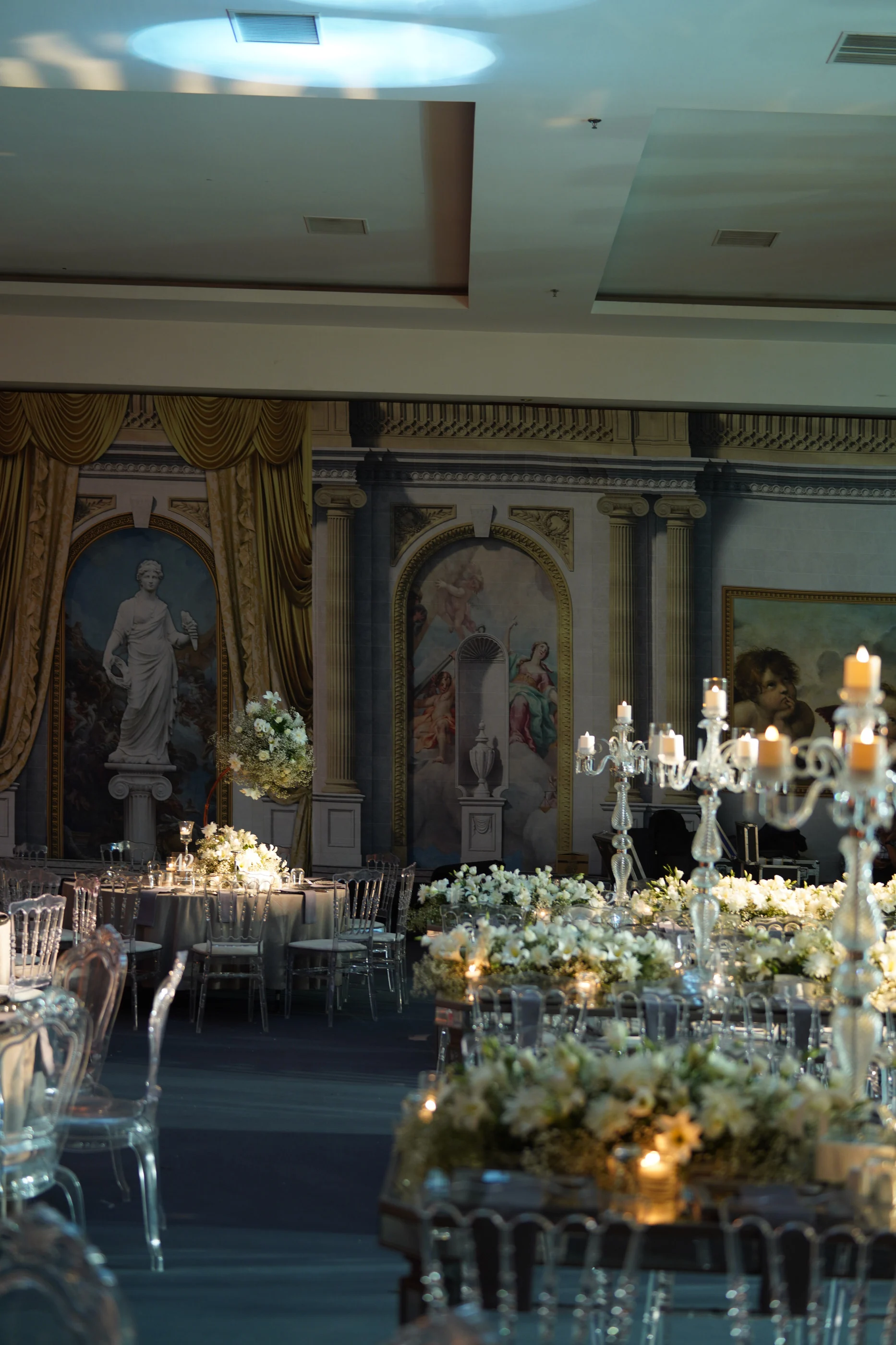 Fresco walls, crystal candelabras and flower-laden tables in cool-toned light