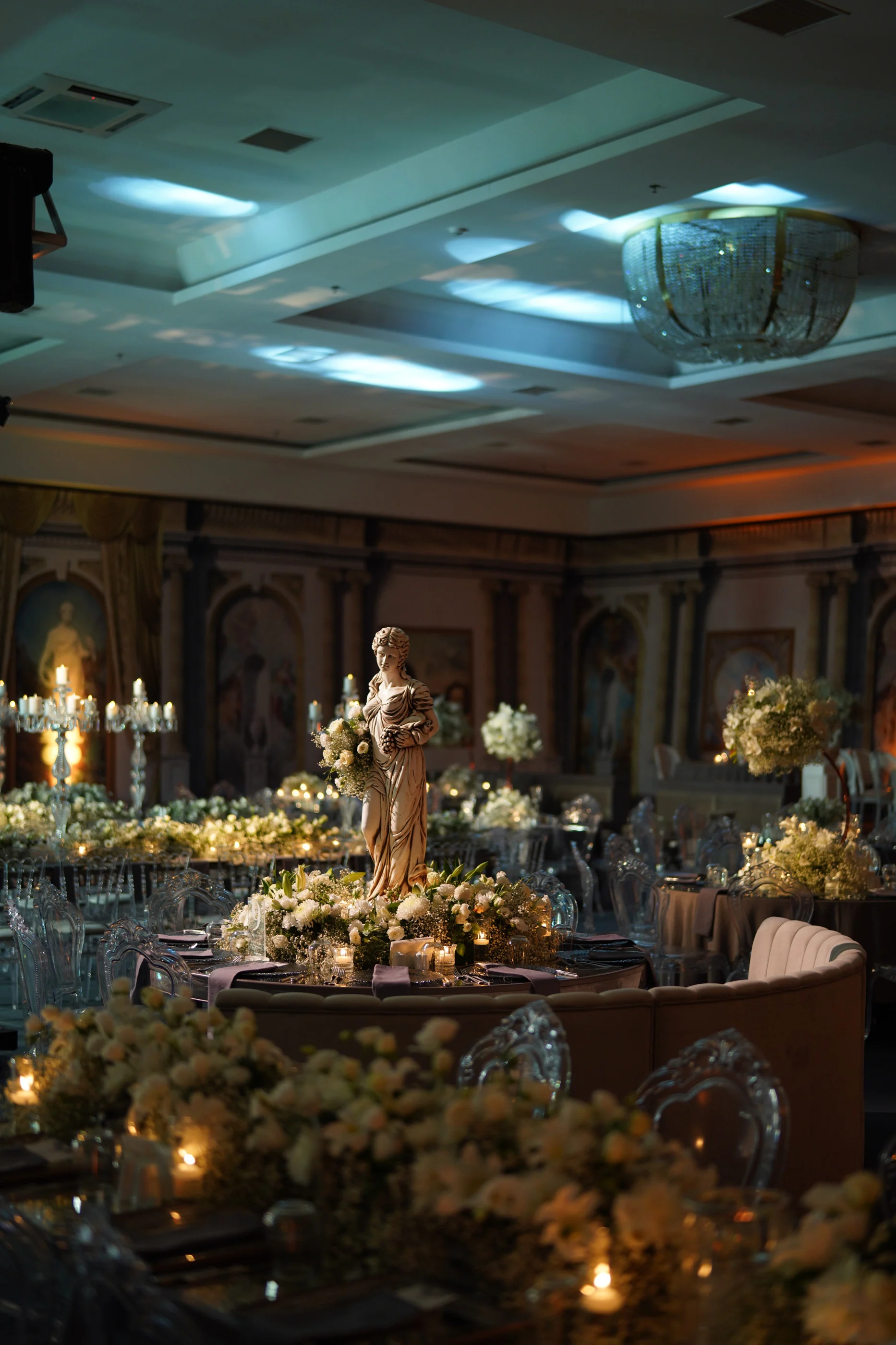 Statue surrounded by flowers and candlelight at the centre of a round banquette