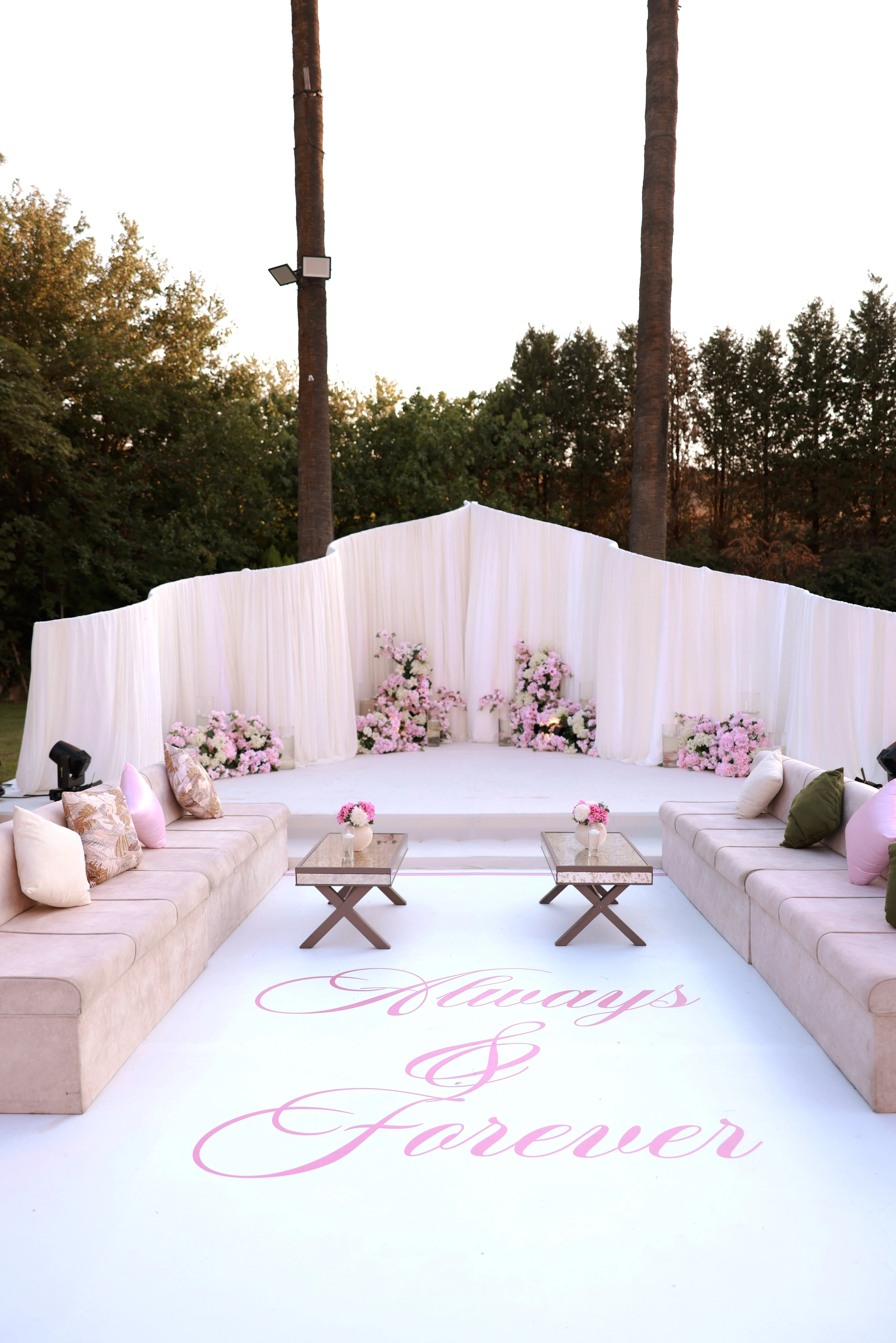 Blush seating area and engagement stage framed by white drapery