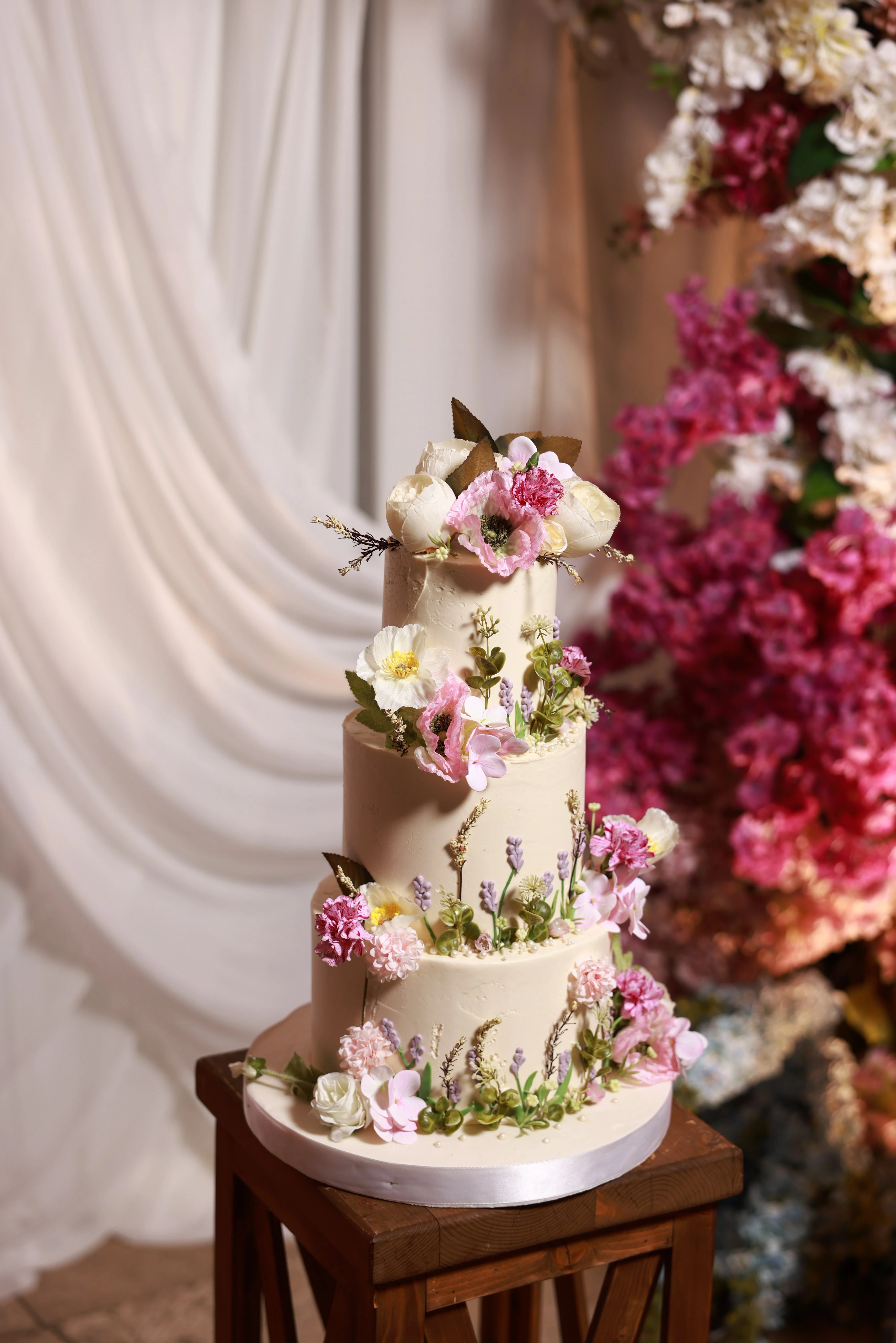 Simple white engagement cake surrounded by flowers