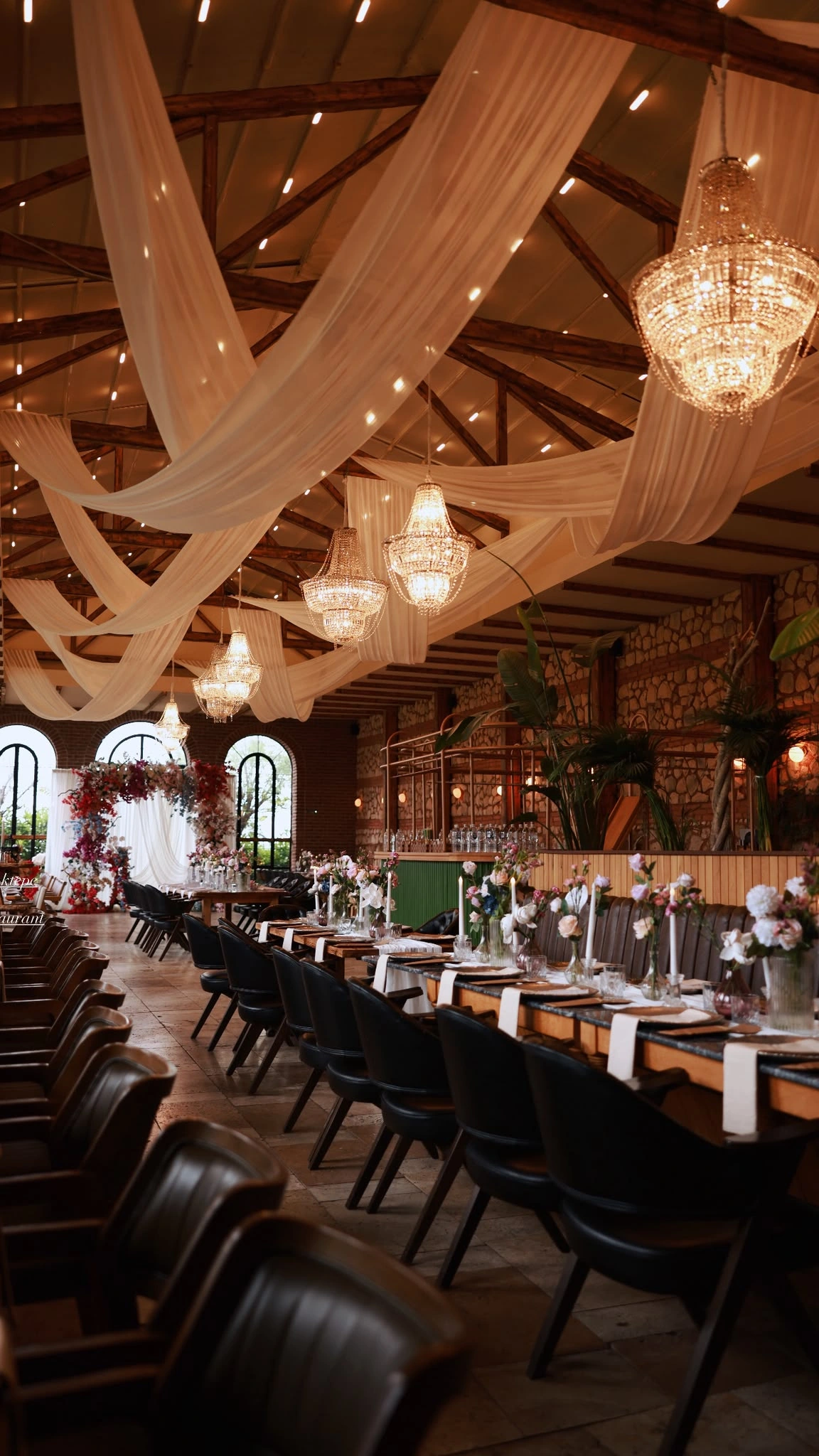 Long rows of black-chaired tables beneath a timber-beamed ceiling swathed in tulle