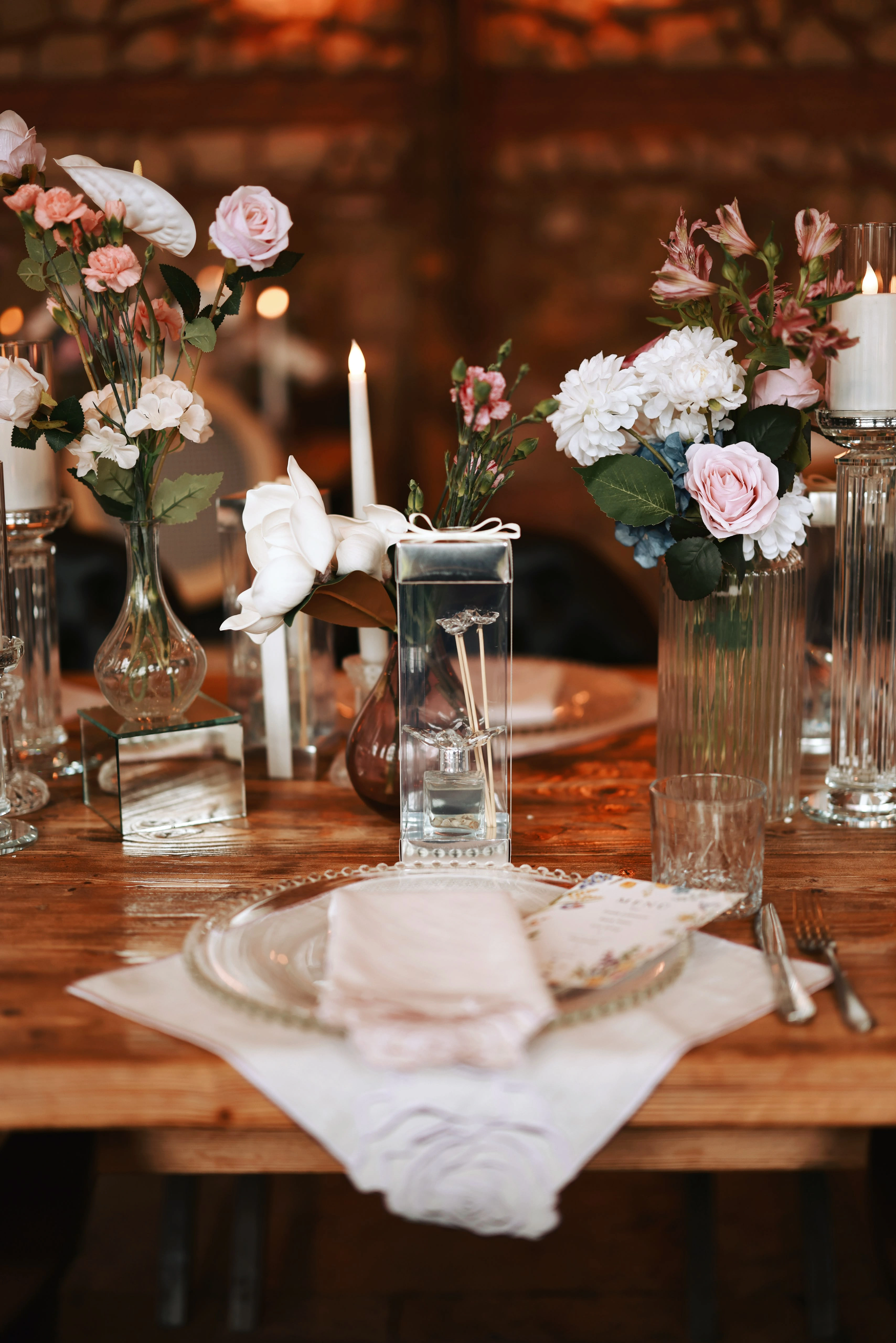 Single place setting with a mirrored cube, slim taper candles and pink carnations