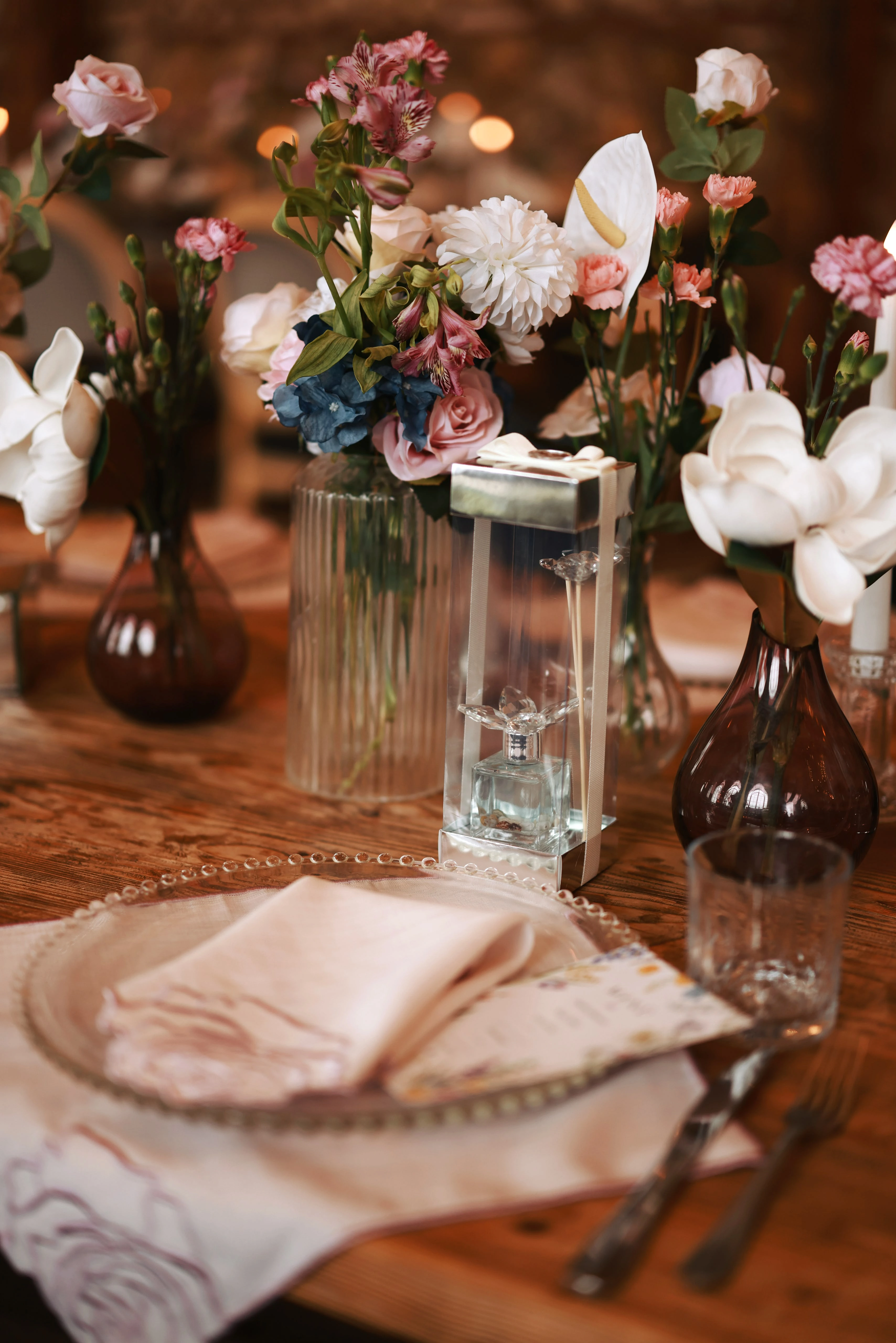 Blush and burgundy flowers with glass candle holders on the table