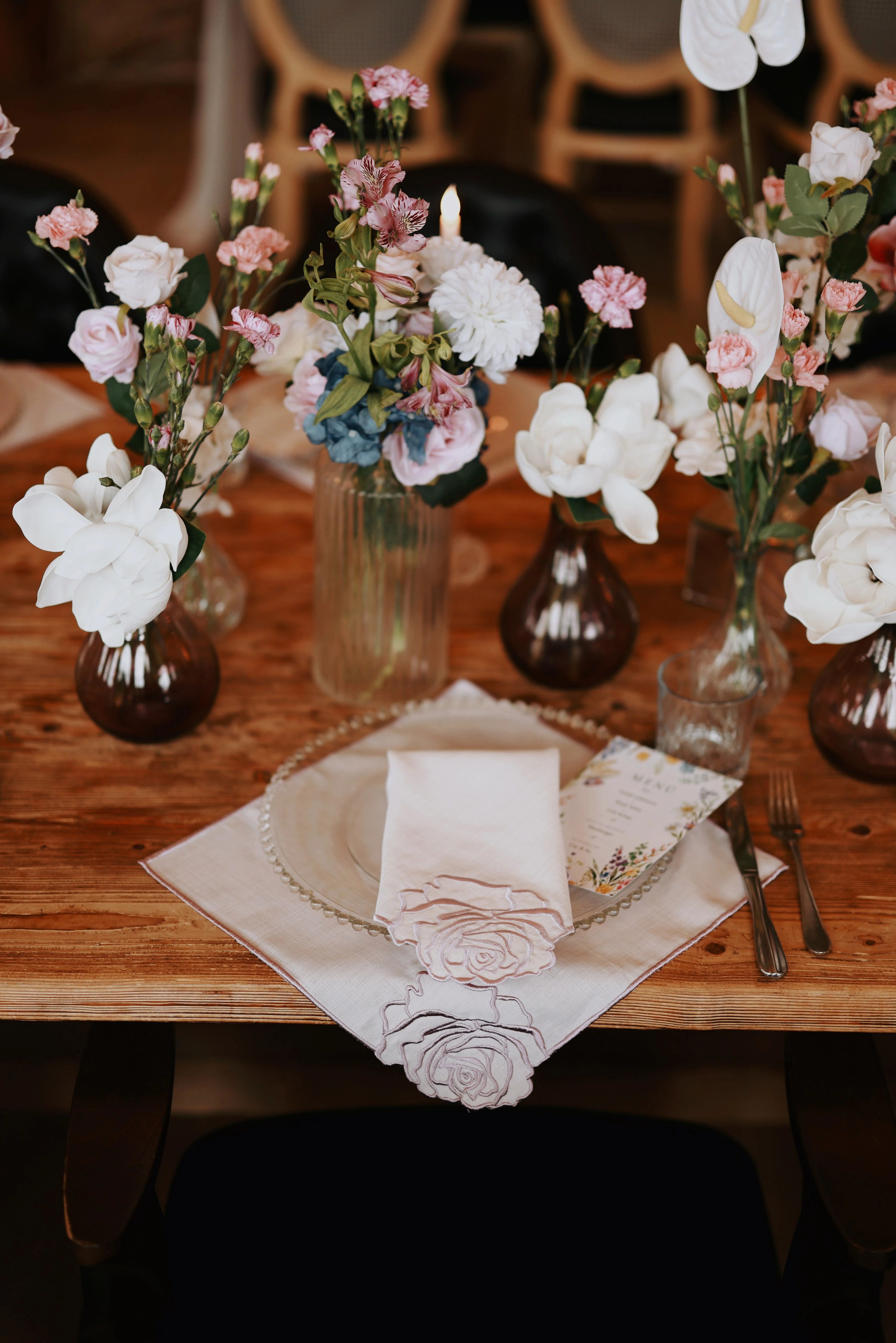Place setting with a blush napkin, patterned plate and glass candle holders