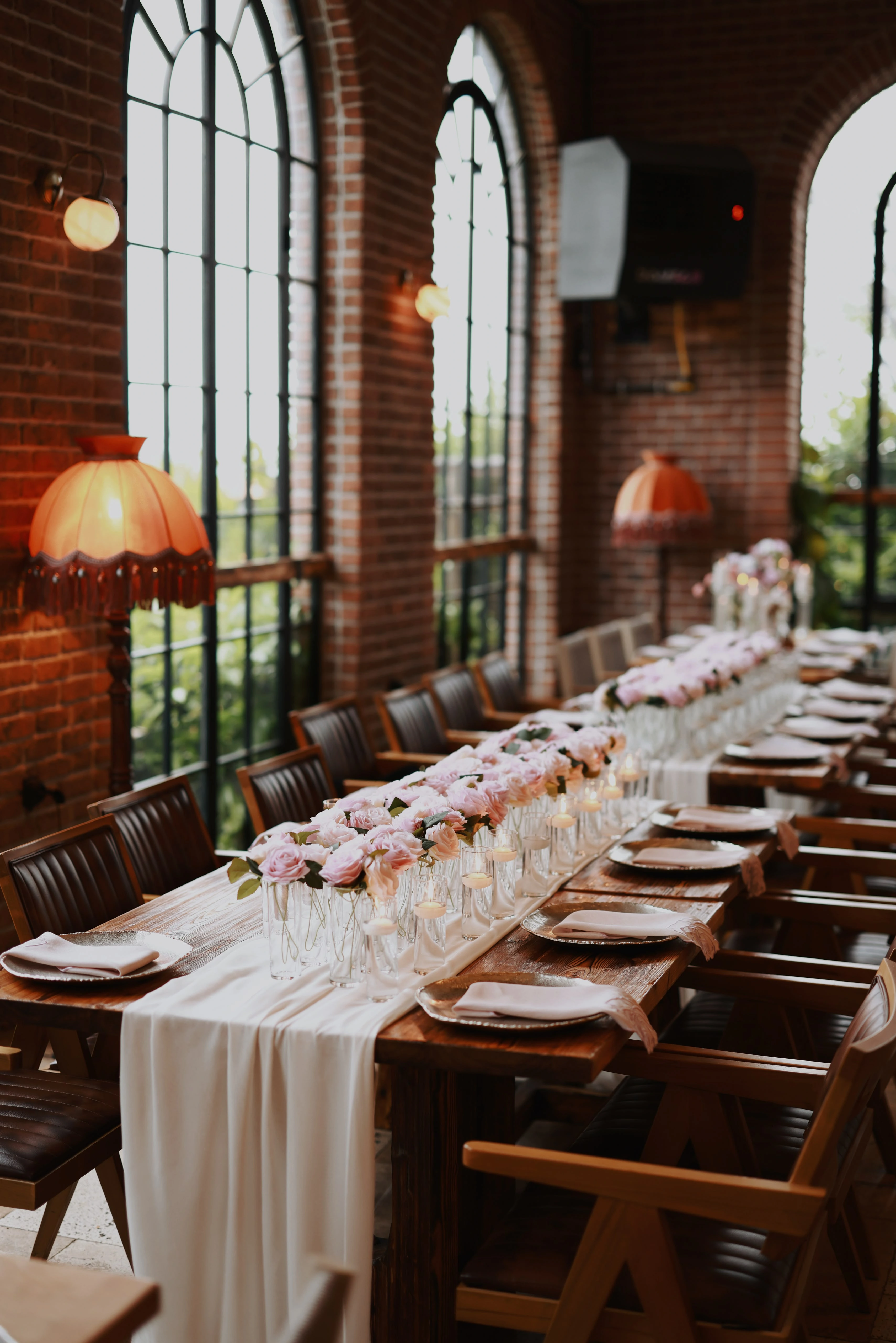 Wide view of the hall with crystal chandeliers and long timber tables