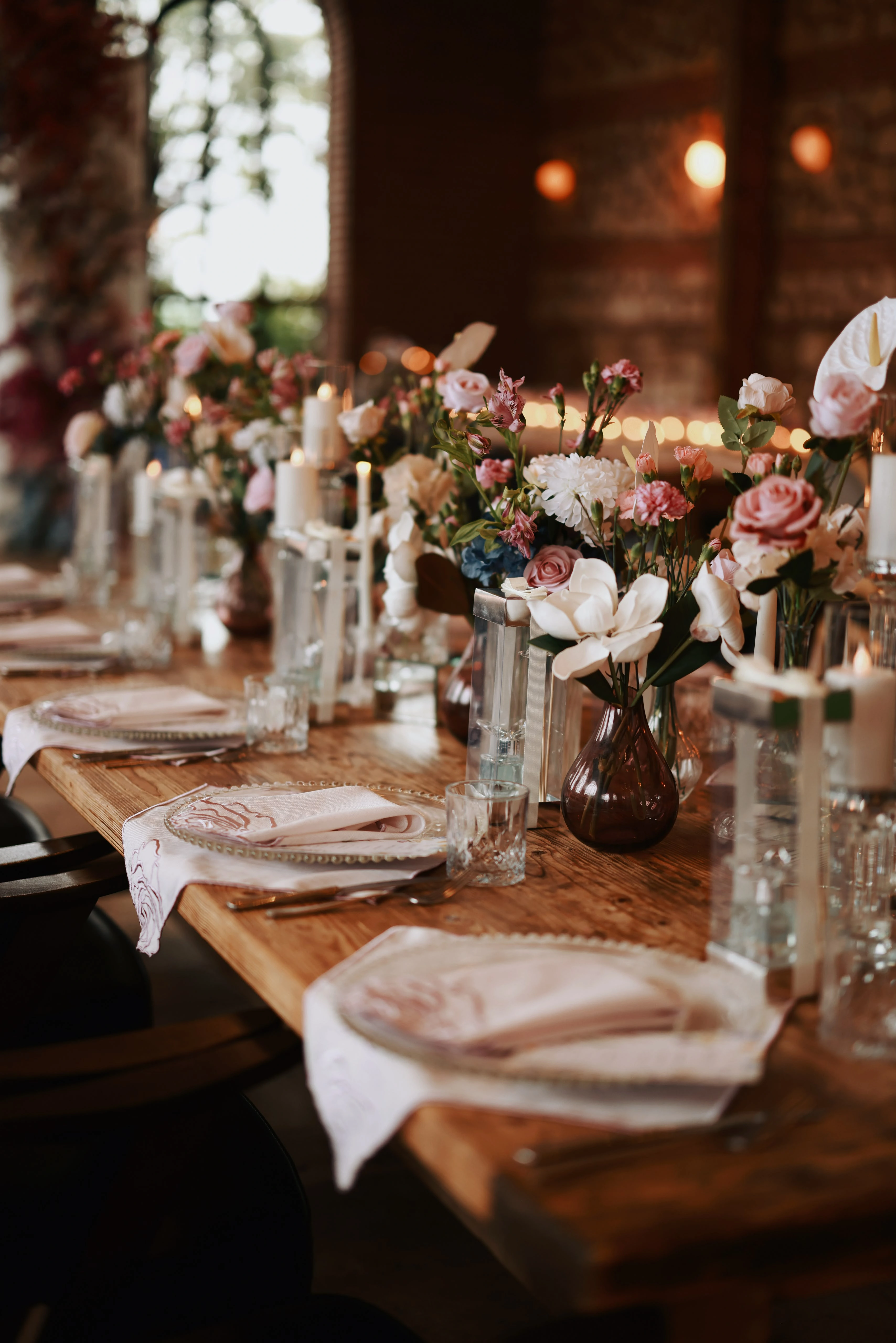 Flowers, candles and glass details on a timber table