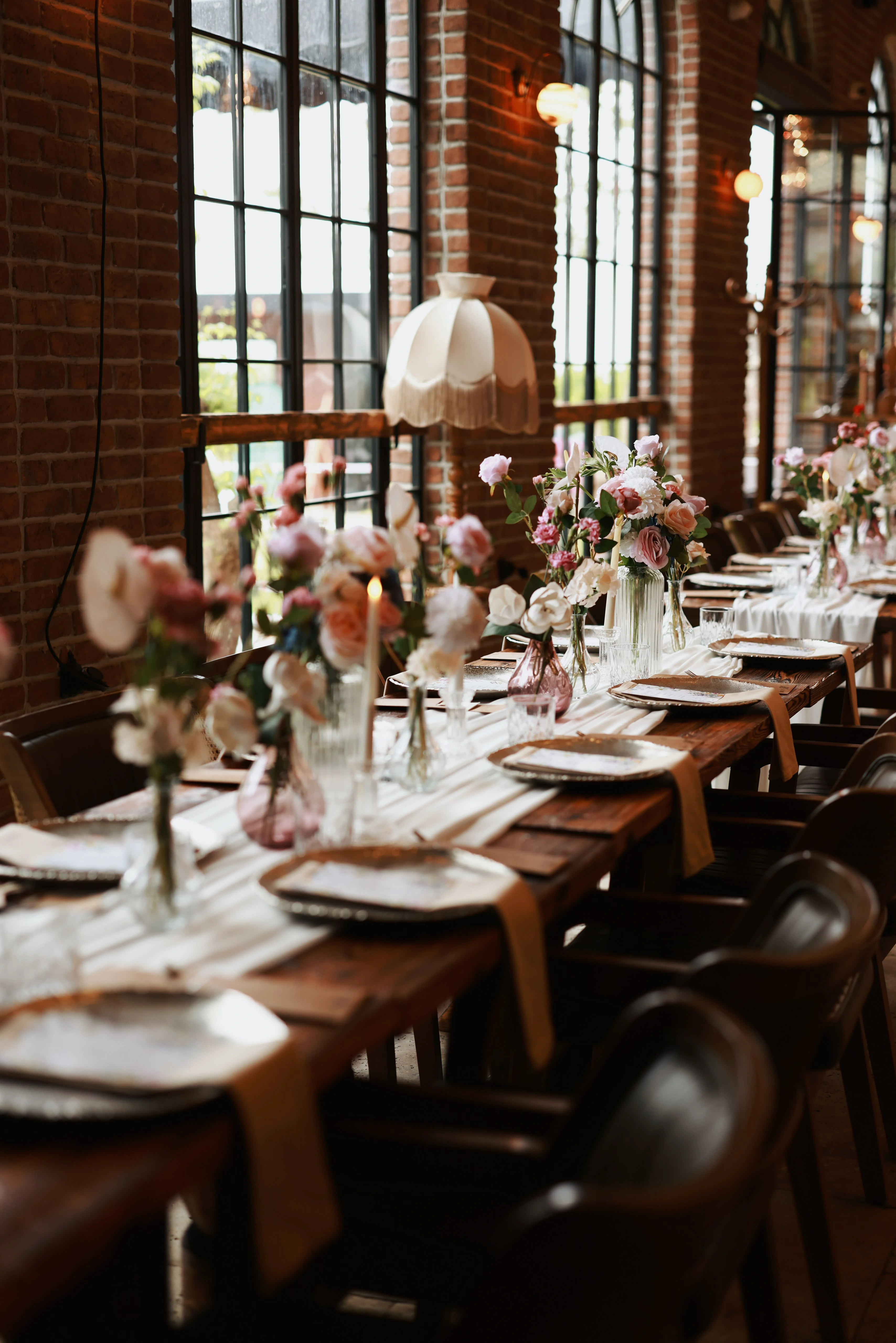 Timber table leading to a floral arch beneath crystal chandeliers
