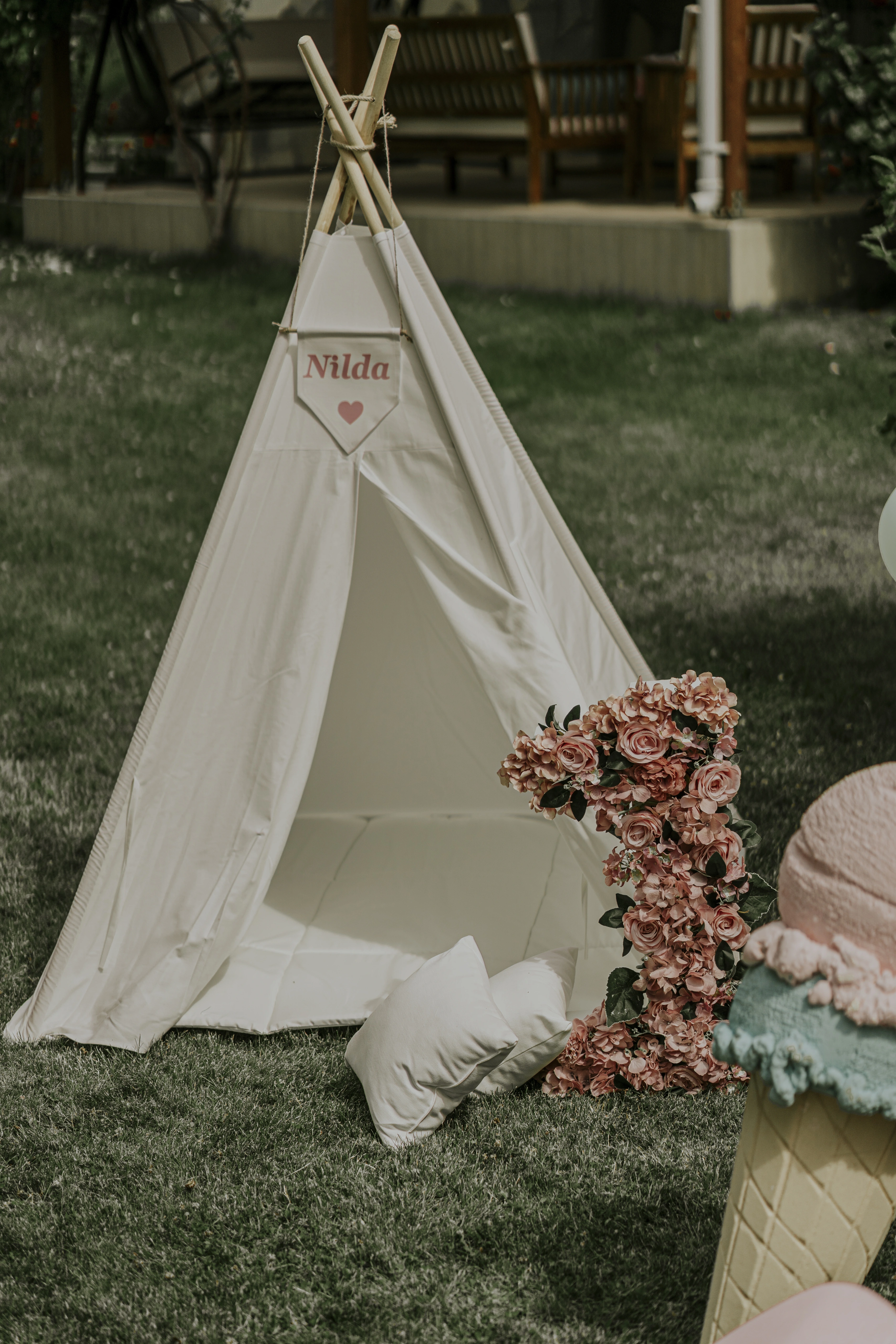 White children's teepee in the garden with a floral number décor and cushions