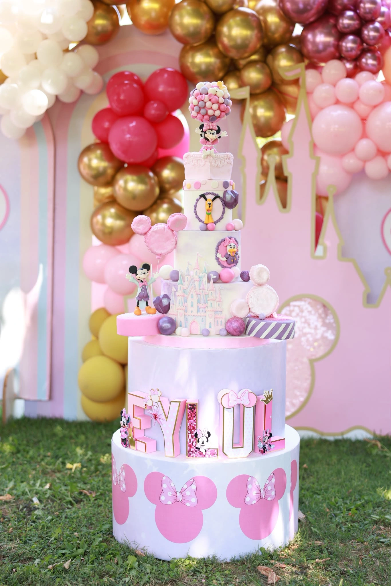 Pembe ve altın balonlar önünde Minnie temalı doğum günü pastası