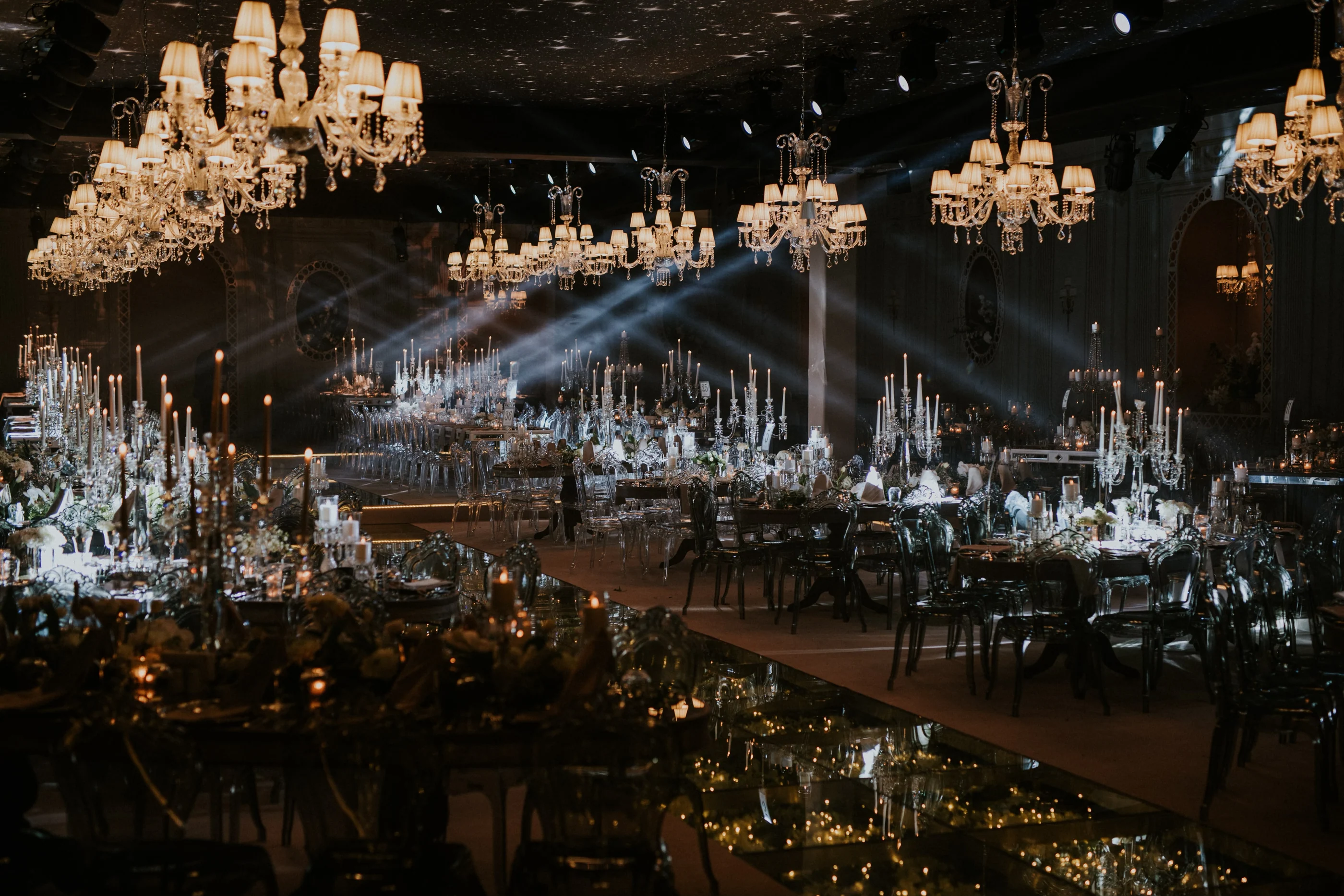 Wide wedding ballroom with crystal chandeliers and crossing beams of light