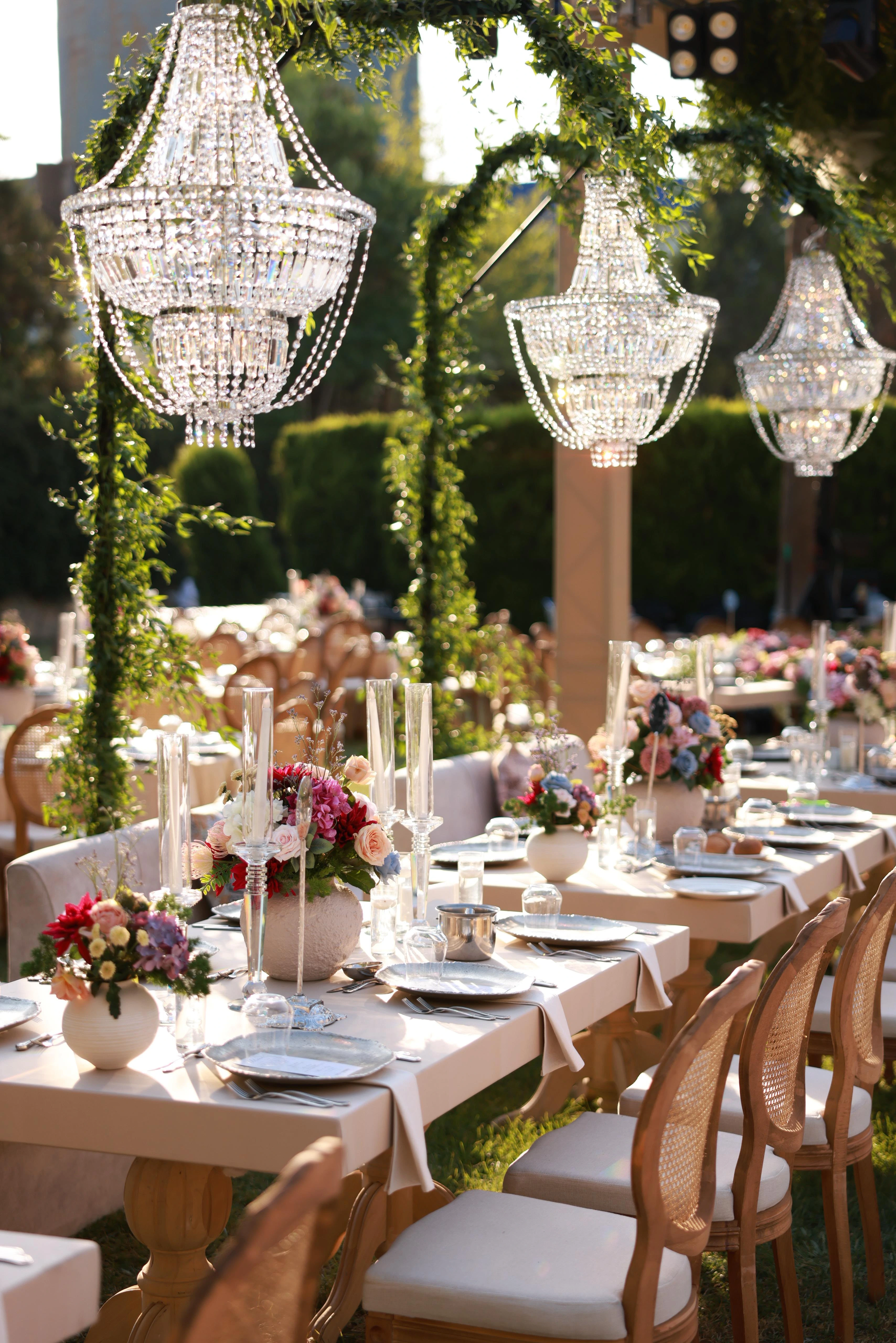 Garden engagement with crystal chandeliers, pastel flowers and wooden chairs, view 1