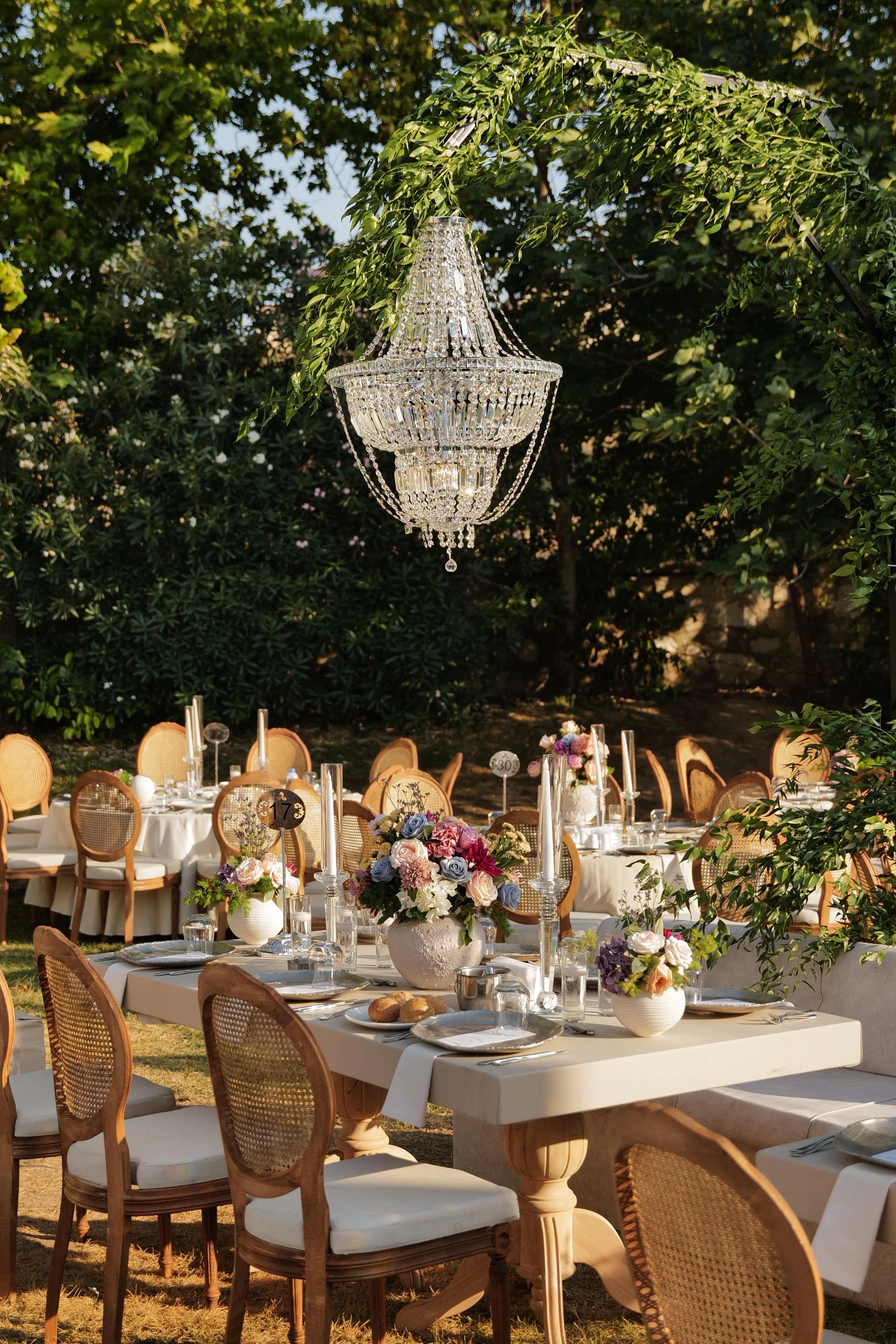 Garden engagement with crystal chandeliers, pastel flowers and wooden chairs, view 2