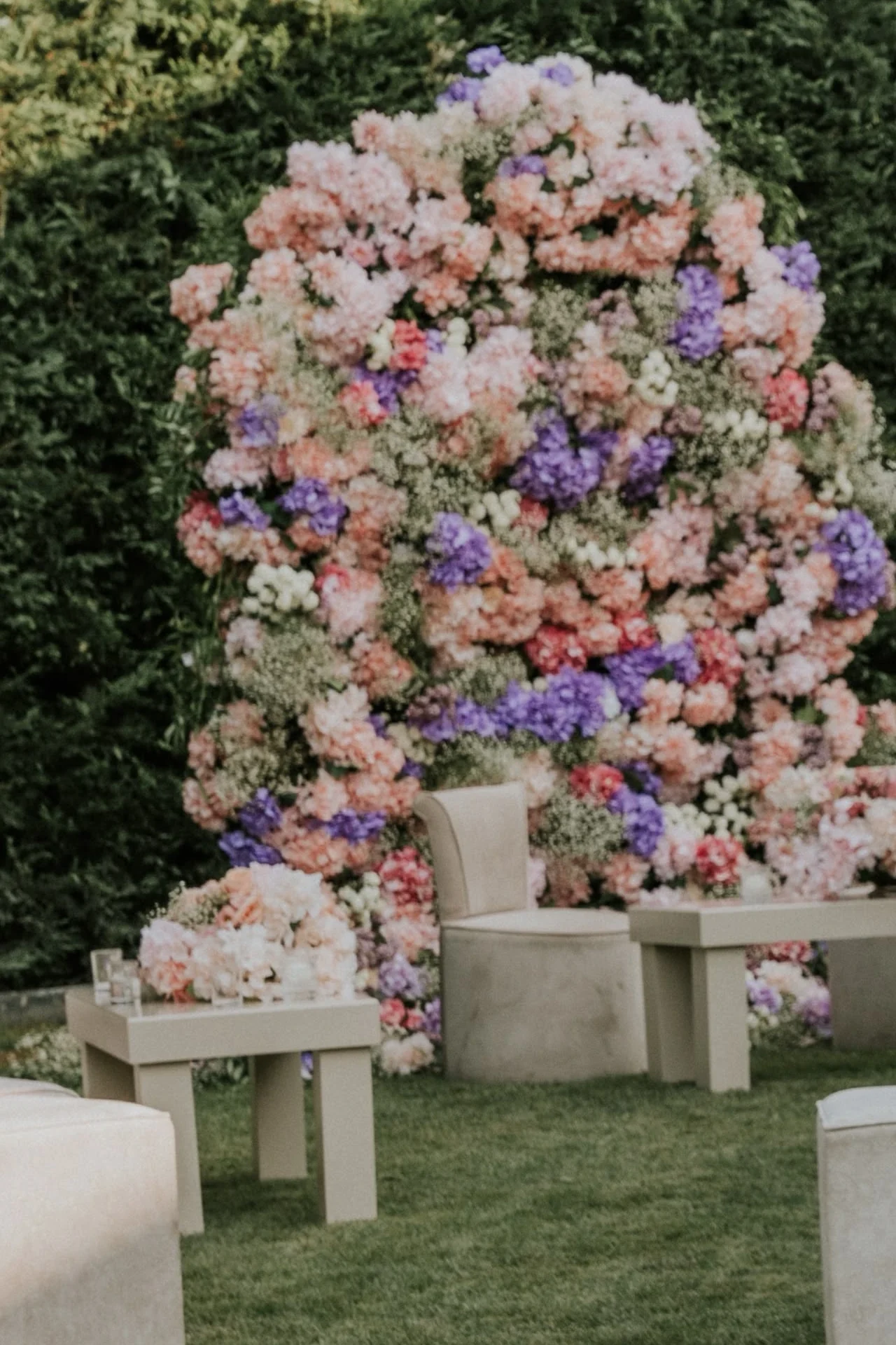 Pink and lilac flower arch with cream lounge seating and hydrangea tables in the garden