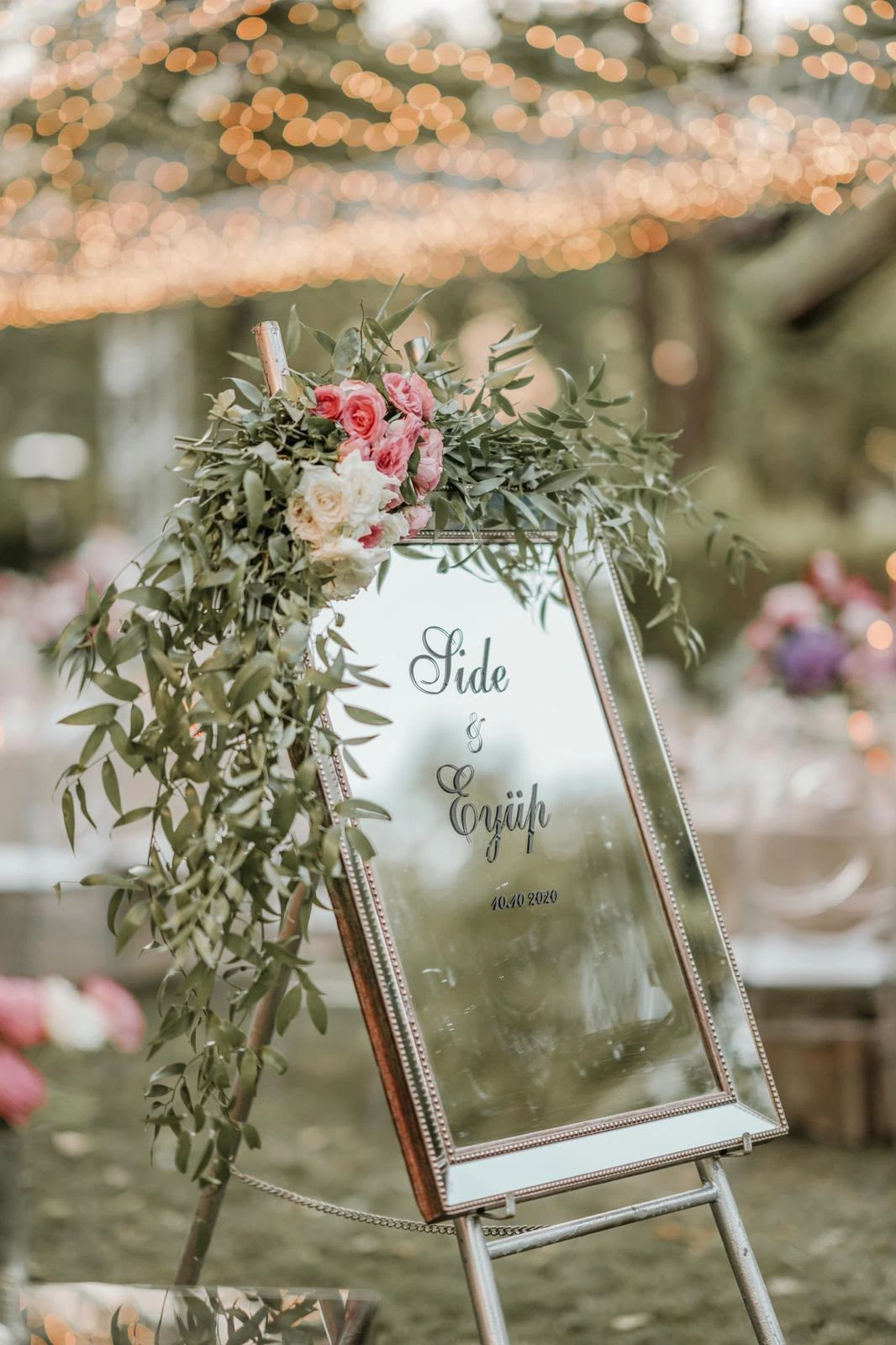 Mirrored welcome board decorated with flowers and greenery