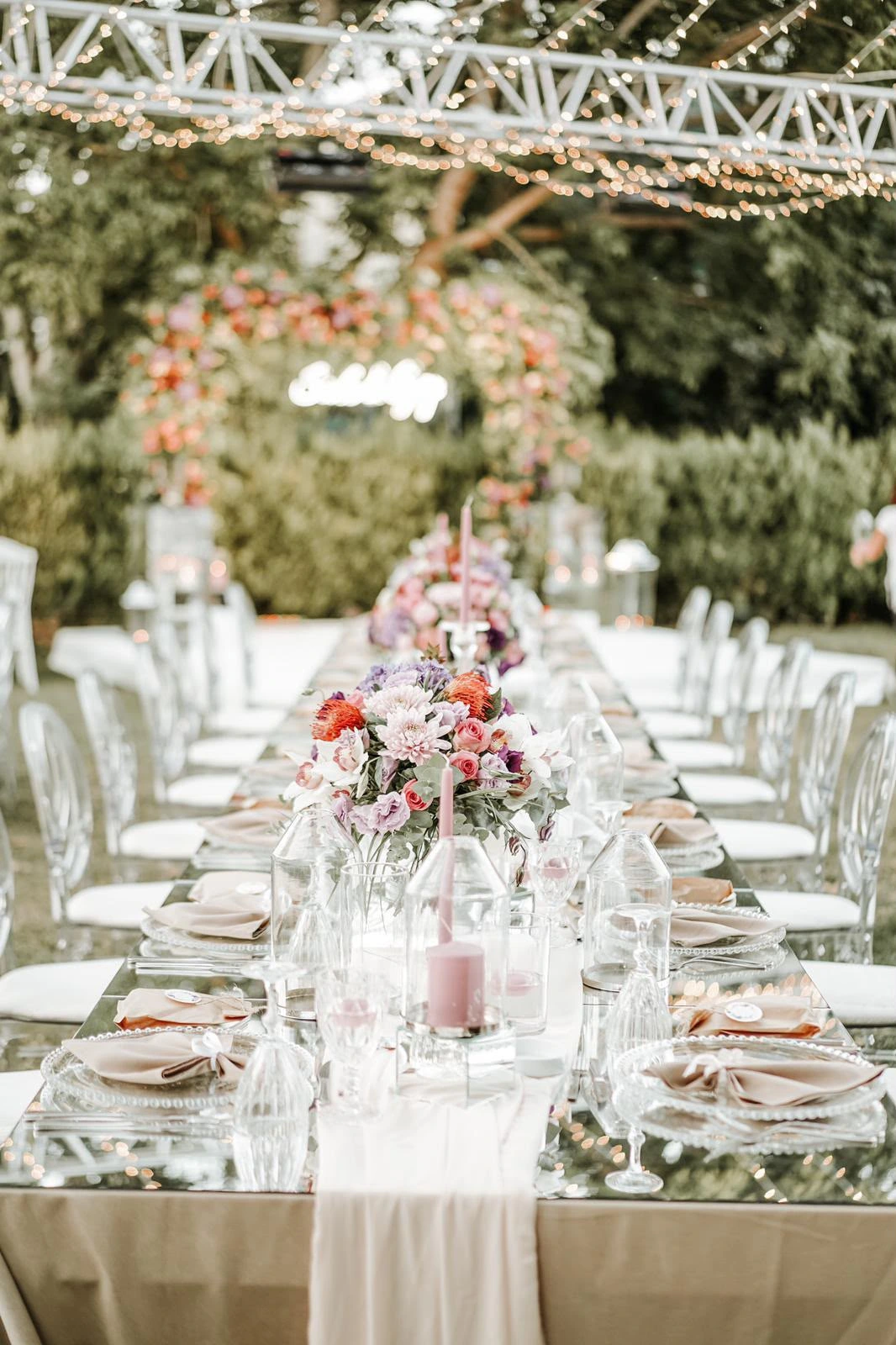 Long mirrored engagement table and a pink floral arch