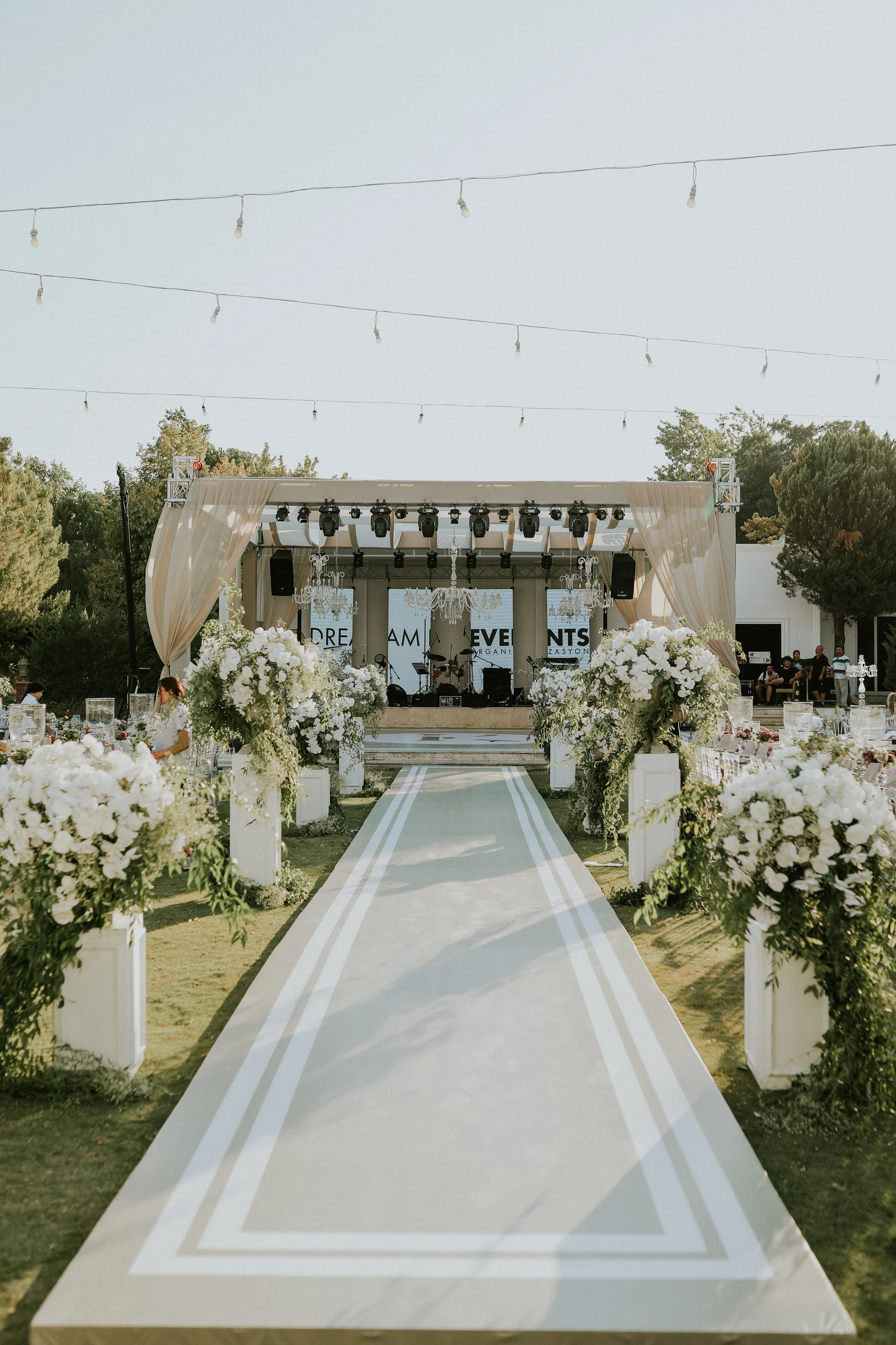 White aisle runner lined with white flower columns leading to the stage