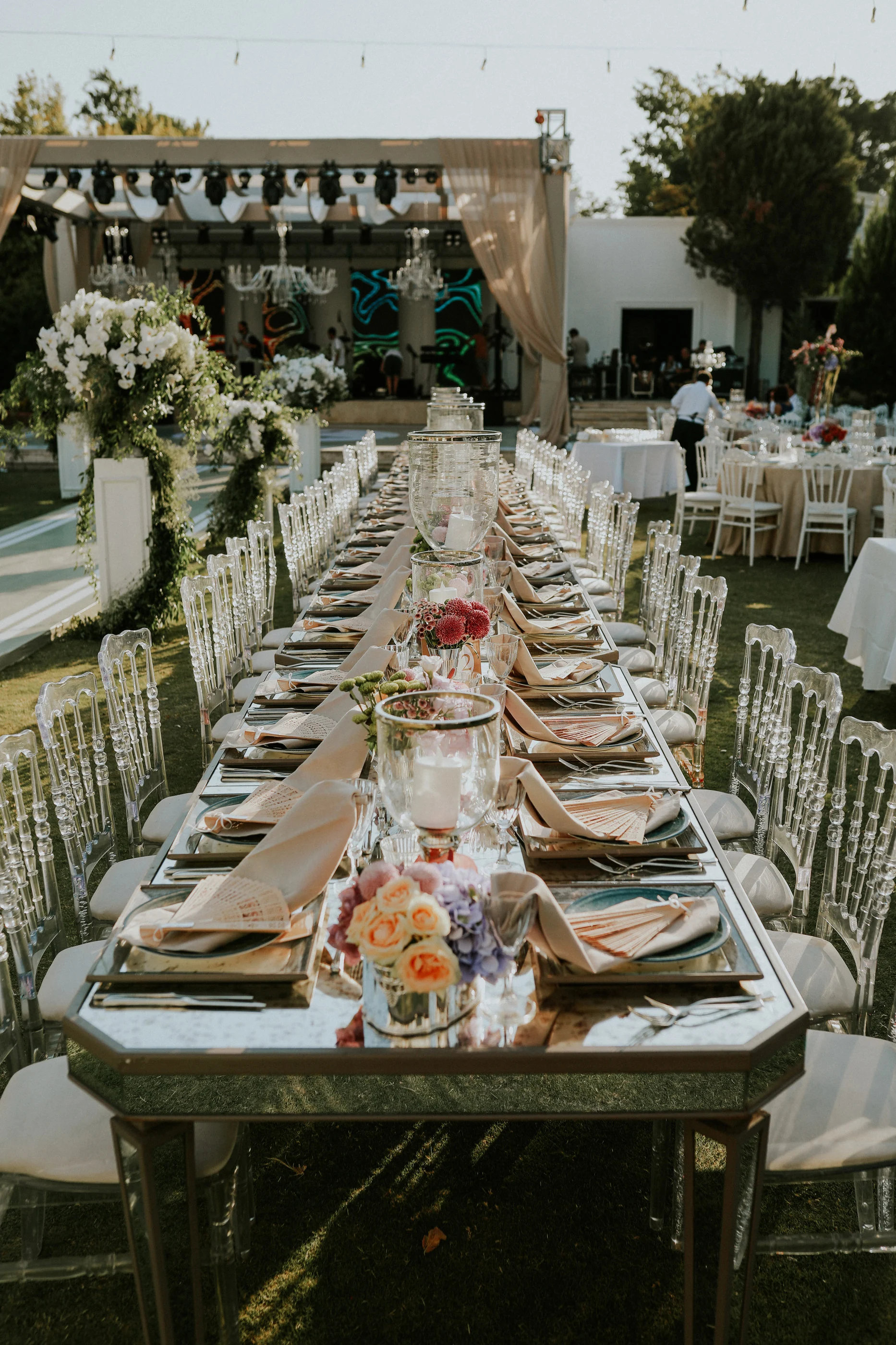 Front view of a mirrored long table with orange roses facing the stage